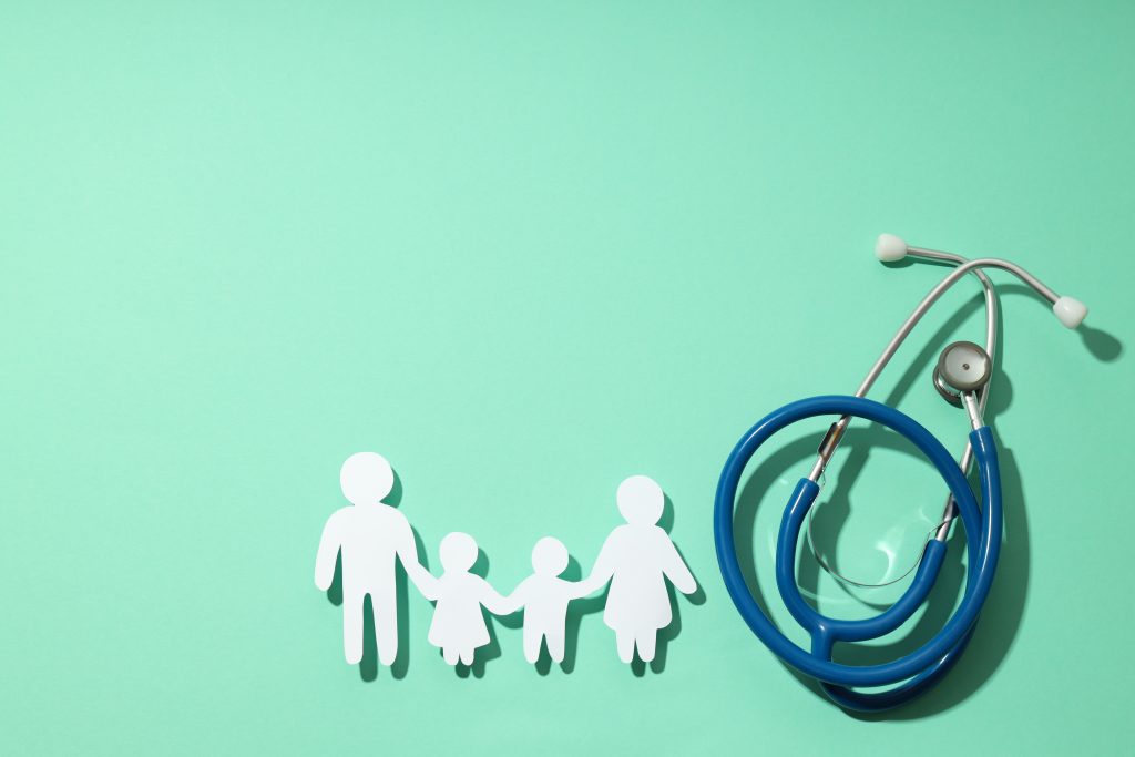 stethoscope and paper cutout of family on turquoise background