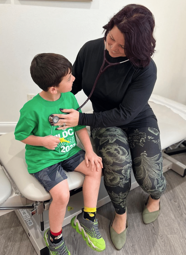 Dr. Nikole listening to young boy's heart with stethoscope
