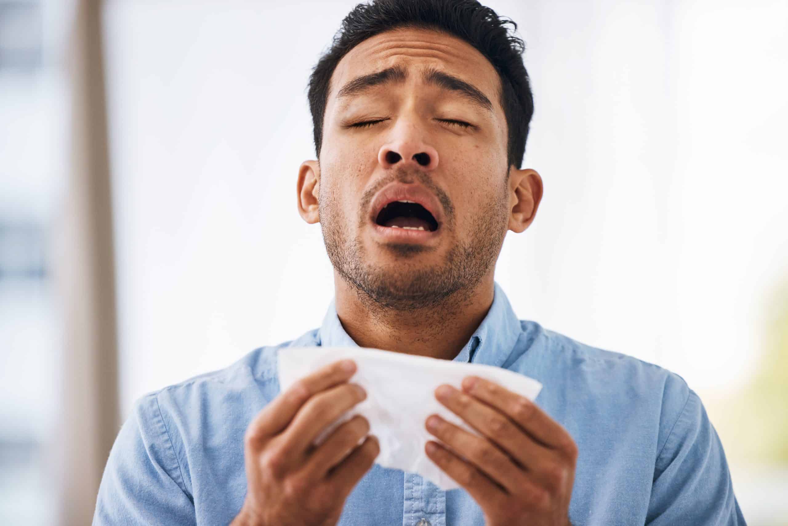 man sneezing with tissue