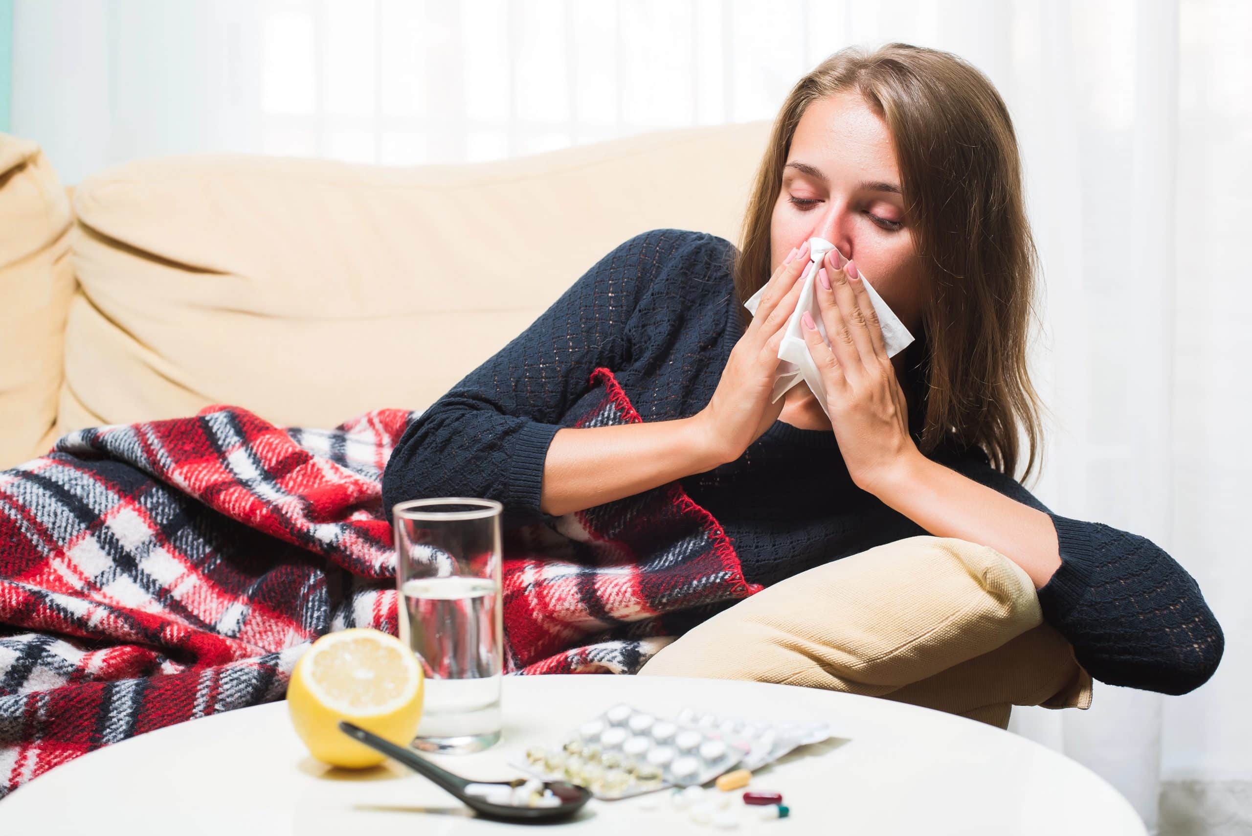sick woman blowing nose on couch